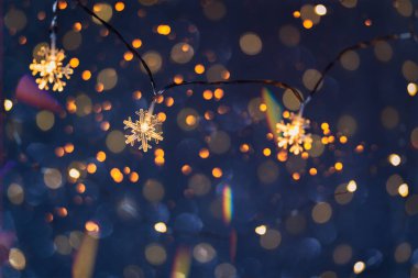 Karanlık bir arka planda Noel çelenkleri. Sıcak peri masalı atmosferi. Seçici olarak ampule odaklan. Yeni yıl kartı