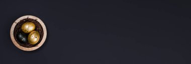 Yumurtalar siyah arka planda altın ve siyaha boyandı. Yuvanın tepesinde üç yumurta var. Metin için kopyalama alanı olan asgari Paskalya kavramı.