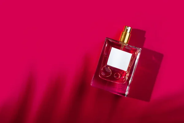 Przezroczysta Butelka Perfum Etykietą Czerwonym Tle Prezentacja Zapachu Przy Świetle — Zdjęcie stockowe
