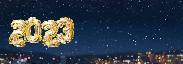 2023年的氦金气球号背景下的夜雪城 用Bokeh点亮节日的花环 新年快乐贺卡 — 图库照片