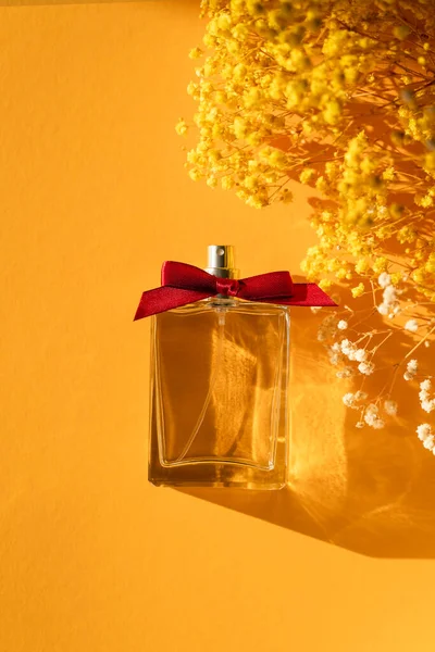 黄色の背景にリボン弓と香水の透明なボトル 昼との香りのプレゼンテーション 美しい影を持つ天然素材のトレンドコンセプト 女性の本質 — ストック写真