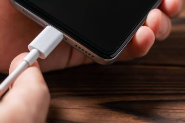 Adam akıllı bir telefonda şarj aletini fişe takıyor. Elektrik bankası olan akıllı telefon kullanan bir adam. Adamın biri cep telefonuyla şarj oluyor.