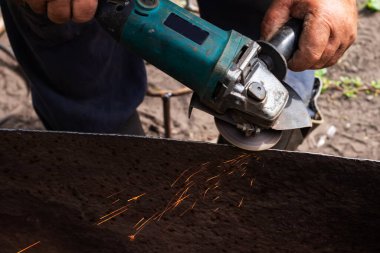 Ustanın elleri, metali öğütücüyle gördü. Metal atölyede çalışıyor. Kapatın.,