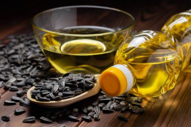 Cam kasede ayçiçeği yağı ve tahta arka planda tahta kaşıkta tohum..