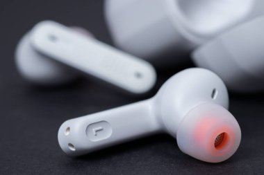 Beyaz kablosuz kulaklık ve karanlık bir arka planda dava.