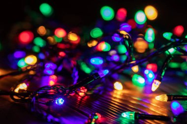 Işıklı ve bedava metin alanlı bir Noel arkaplanı. Noel ışıkları sınırda. Ahşap arka planda parıldayan renkli Noel ışıkları. Yeni yıl. Noel zamanı. Dekorasyon. Çelenk.