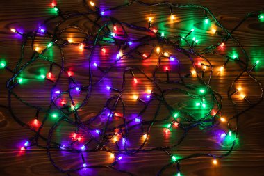 Işıklı ve bedava metin alanlı bir Noel arkaplanı. Noel ışıkları sınırda. Ahşap arka planda parıldayan renkli Noel ışıkları. Yeni yıl. Noel zamanı. Dekorasyon. Çelenk.