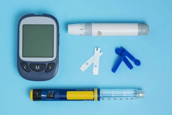 stock image Measuring blood sugar. Glucometer, insulin pen, lancet and test strip on a blue background