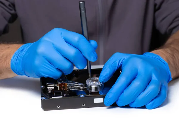 Repair Hard disk. Hands of master in gloves with screwdriver repair the computer hard drive. Data cleaning, HDD recovery