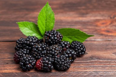 Ahşap arka planda yaprakları olan böğürtlenler..