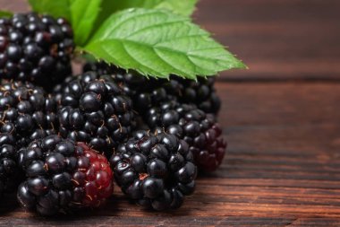 Ahşap arka planda yaprakları olan böğürtlenler..