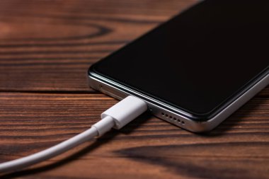 Şarj pili akıllı telefon ahşap masada.