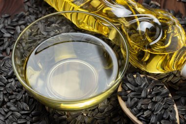 Cam kasede ayçiçeği yağı ve tahta arka planda tahta kaşıkta tohum..