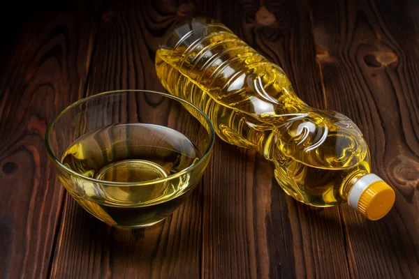Sunflower oil in bottles with glass bowl on wooden background.