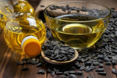 Cam kasede ayçiçeği yağı ve tahta arka planda tahta kaşıkta tohum..