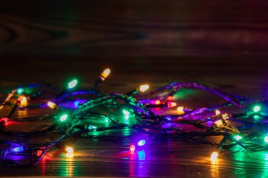 Işıklı ve bedava metin alanlı bir Noel arkaplanı. Noel ışıkları sınırda. Ahşap arka planda parıldayan renkli Noel ışıkları. Yeni yıl. Noel zamanı. Dekorasyon. Çelenk.