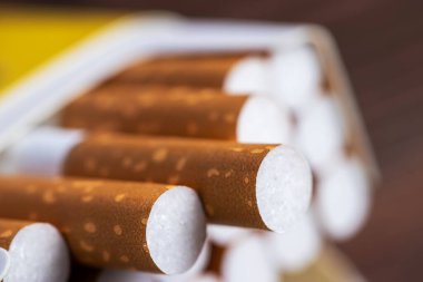 Pakette sigara. Sarı filtre. Sağlığa zarar verir. Kötü alışkanlık. Masada bir paket sigara var. açık sigara paketi.