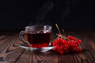 Viburum ve bardakta viburnum çayı, ahşap arka planda mevsimlik meyveli içecek..
