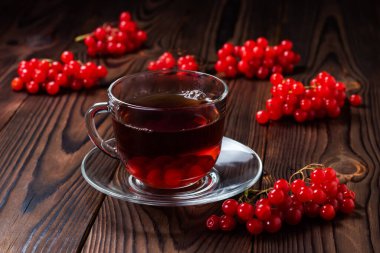 Ahşap arka planda organik viburnum çayı, taze viburnum üzümlü sıcak sonbahar içeceği. Ballı ve tarçınlı Viburnum çayı.