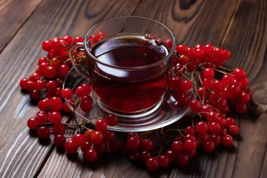 Viburum ve bardakta viburnum çayı, ahşap arka planda mevsimlik meyveli içecek..