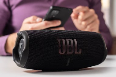 Dnioro Ukraine. 27 january 2023: Bluetooth speaker JBL Charge 5 with smart phone. Man using bluetooth speaker and smartphone.