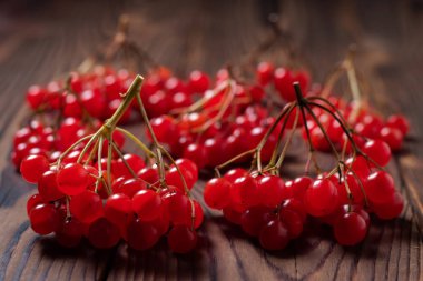 Dalları kırmızı Viburnum böğürtlenleri, ok tahtası, ahşap arka planda.