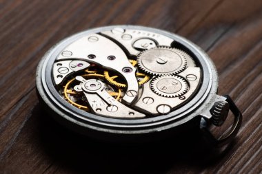 Clock mechanism macro shot on wooden background.