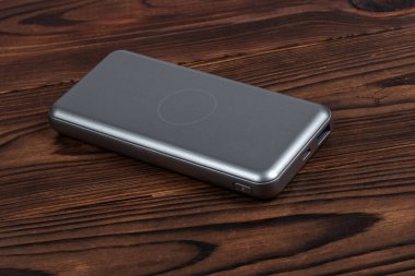 Power bank for charging mobile devices on wooden background. External battery for mobile devices