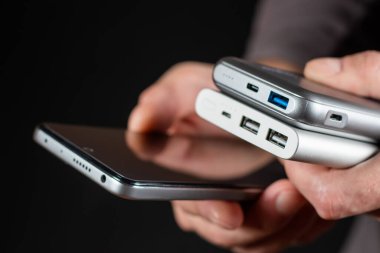 Man hands are holding a smartphone and a powerbank charger. Still life modern digital concept