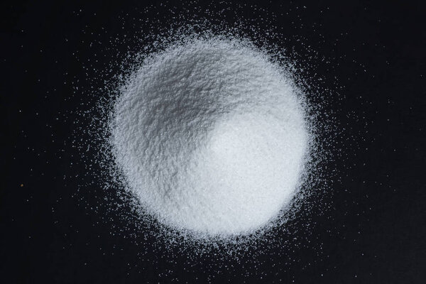 White quartz sand on a black background in the form of a slide. quartz sand is used in finishing construction materials, water treatment and agriculture top view