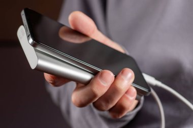 adam telefon ve şarj tutuyor. Powerbank ve smartphone elinde. Güç tasarrufu cihazı gücü banka smartphone.