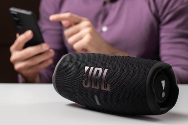 Dnioro Ukraine. 27 january 2023: Bluetooth speaker JBL Charge 5 with smart phone. Man using bluetooth speaker and smartphone.