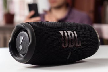 Dnioro Ukraine. 27 january 2023: Bluetooth speaker JBL Charge 5 with smart phone. Man using bluetooth speaker and smartphone.