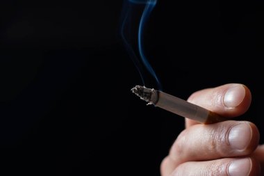 sigara yakma ile el ve siyah arka plan üzerine duman.