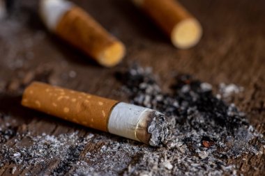 Siyah arka plan ile ahşap masada sigara izmariti.