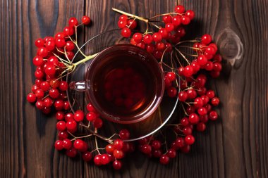 Ahşap arka planda organik viburnum çayı, taze viburnum üzümlü sıcak sonbahar içeceği. Ballı ve tarçınlı Viburnum çayı.