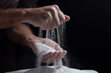 Erkeklerin elleri avuçlarında kum tutar ve parmaklarından kum taneleri dökülür. Hayatın akışı kavramı