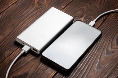 Powerbank ve akıllı telefonu ahşap masaya yükle.