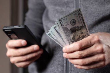 İş adamı bize dolar banknotları tutuyor. Akıllı telefondan bak..