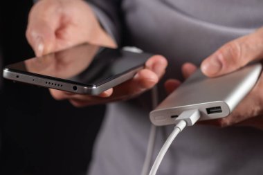 The men hand hold the phone and charger, powerbank and smart phone is connecting, energy.