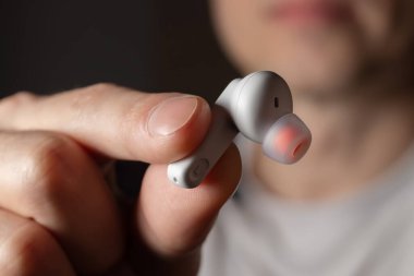 Wireless in-ear white headphones in hand. clipart