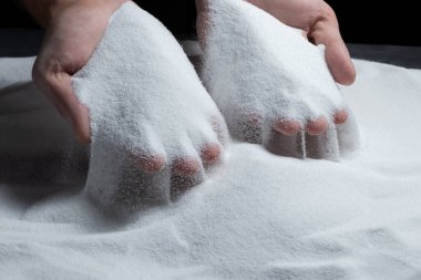 Siyah arka plandaki parmaklar aracılığıyla kum. Hayatın akışı kavramı..