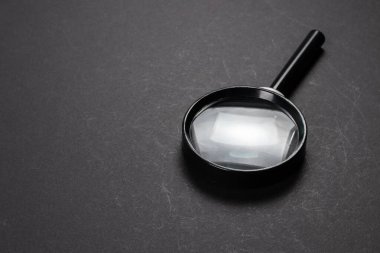 Siyah desenli büyüteç arka planda gölgeli.