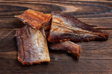 Ahşap zeminde kurutulmuş balık parçaları. Kuru biberli Pollack. Biberli Amber..