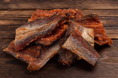 Ahşap zeminde kurutulmuş balık parçaları. Kuru biberli Pollack. Biberli Amber..