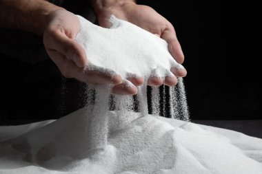 Erkeklerin elleri avuçlarında kum tutar ve parmaklarından kum taneleri dökülür. Hayatın akışı kavramı