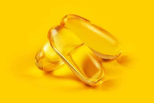 stock image Three capsules Omega 3 on yellow background. Health care concept.