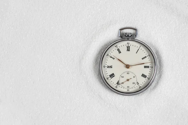Old watch on white sand copy space.