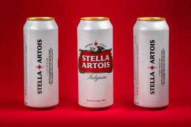 Ukrayna. Dinyeper. 20 Mart 2023: Kırmızı zemin üzerinde üç kutu büyük Belçika birası Stella Artois. Alüminyum kutu Stella Artois birası siyah arka planda.