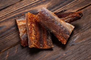 Ahşap zeminde kurutulmuş balık parçaları. Kuru biberli Pollack. Biberli Amber..